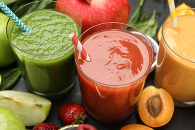 Photo of Superfood. Refreshing smoothies in glasses and ingredients on dark table, closeup