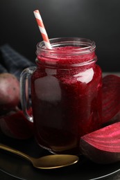 Photo of Superfood. Refreshing smoothie in mason jar and beetroot on table against dark background, closeup