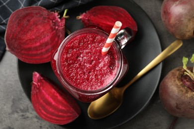 Photo of Superfood. Refreshing smoothie in mason jar and beetroots on grey textured table, flat lay