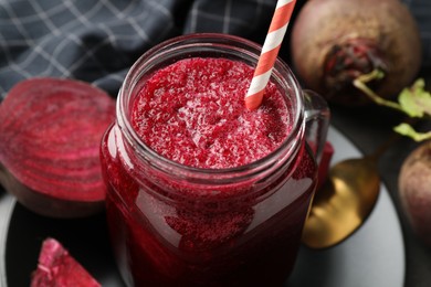 Photo of Superfood. Refreshing smoothie in mason jar and beetroots on dark table, closeup