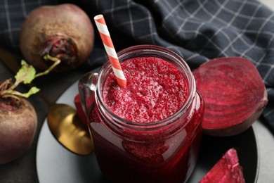 Photo of Superfood. Refreshing smoothie in mason jar and beetroots on dark table, closeup