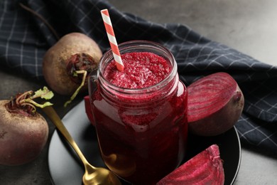 Photo of Superfood. Refreshing smoothie in mason jar and beetroots on dark textured table, closeup