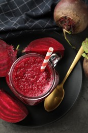 Photo of Superfood. Refreshing smoothie in mason jar and beetroots on dark textured table, flat lay