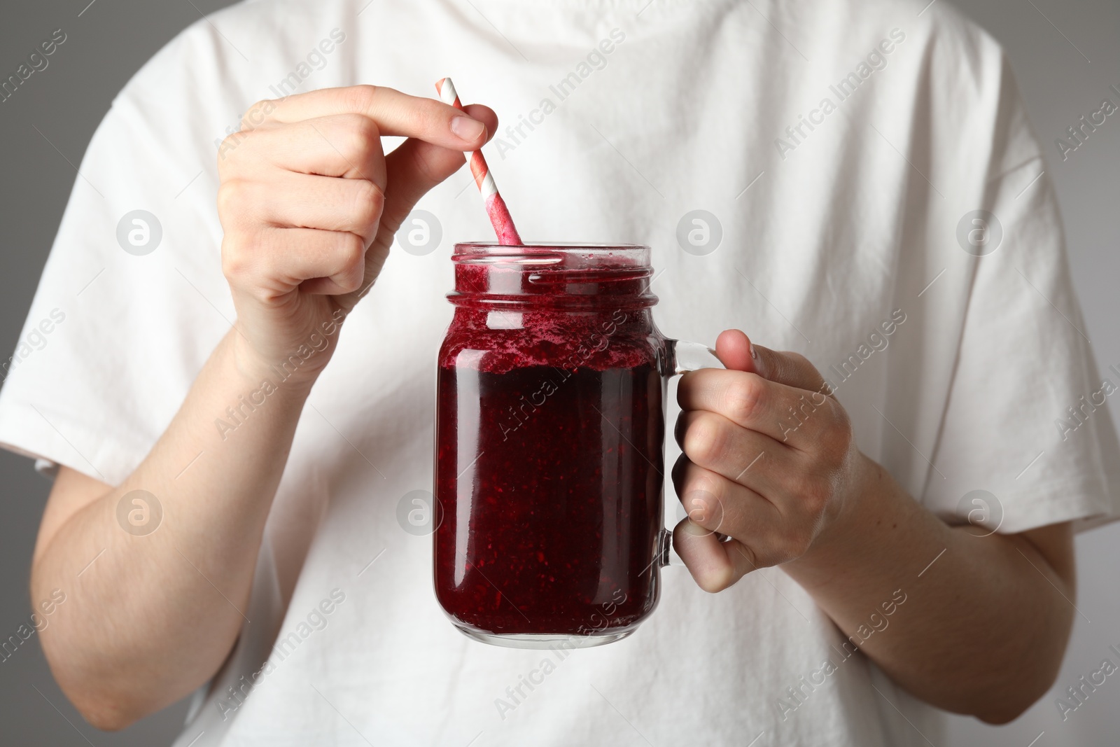 Superfood. Woman with mason jar of tasty smoothie against grey background, closeup Photo of Superfood. Woman with mason jar of tasty smoothie against grey background, closeup