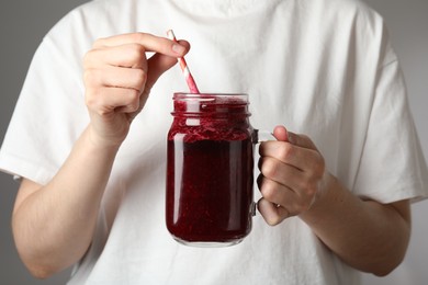 Photo of Superfood. Woman with mason jar of tasty smoothie against grey background, closeup