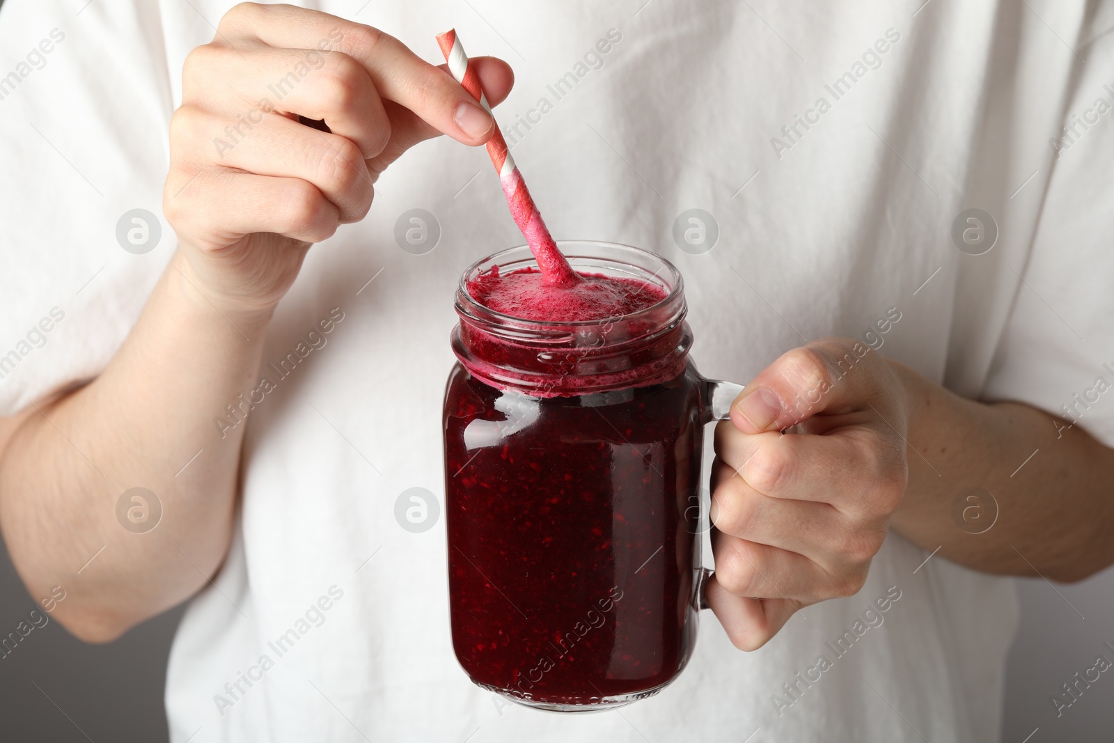 Superfood. Woman with mason jar of tasty smoothie against grey background, closeup Photo of Superfood. Woman with mason jar of tasty smoothie against grey background, closeup