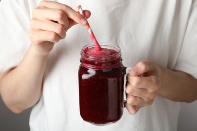 Photo of Superfood. Woman with mason jar of tasty smoothie against grey background, closeup