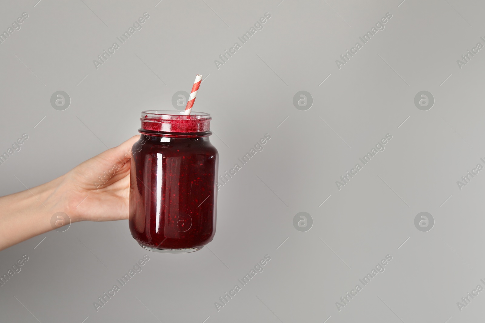 Superfood. Woman with mason jar of tasty smoothie against grey background, closeup. Space for text Photo of Superfood. Woman with mason jar of tasty smoothie against grey background, closeup. Space for text