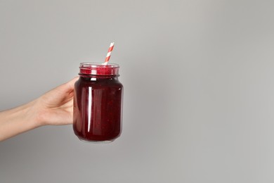 Photo of Superfood. Woman with mason jar of tasty smoothie against grey background, closeup. Space for text