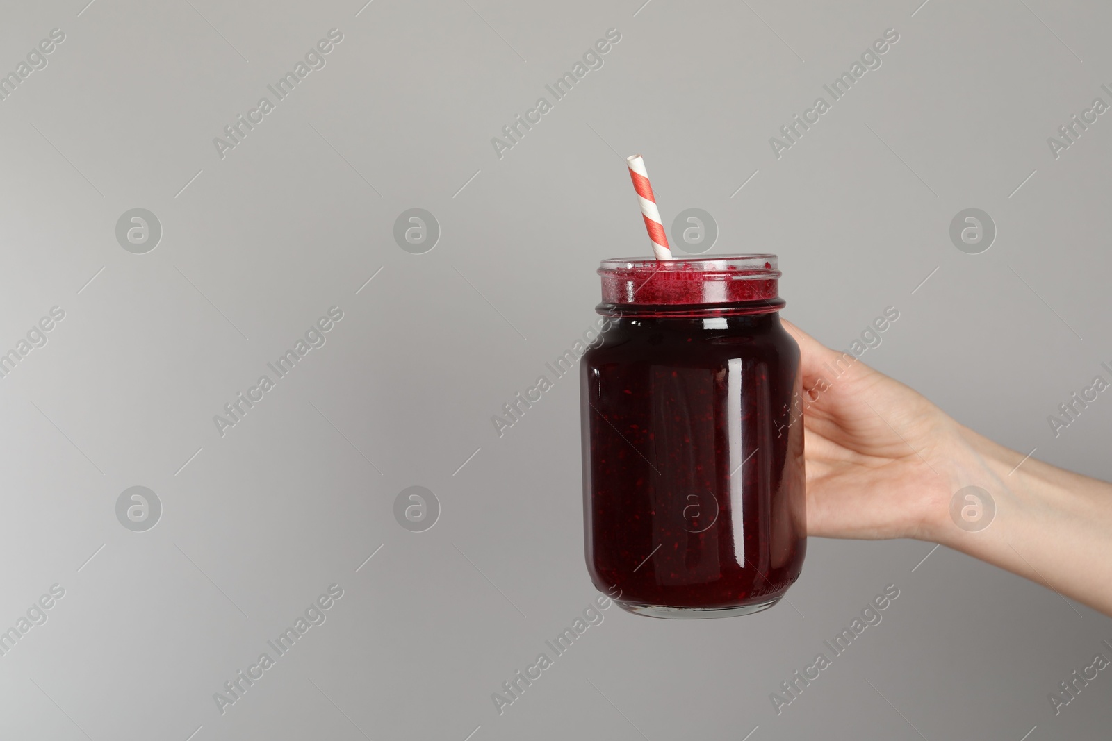 Superfood. Woman with mason jar of tasty smoothie against grey background, closeup. Space for text Photo of Superfood. Woman with mason jar of tasty smoothie against grey background, closeup. Space for text