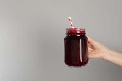 Photo of Superfood. Woman with mason jar of tasty smoothie against grey background, closeup. Space for text