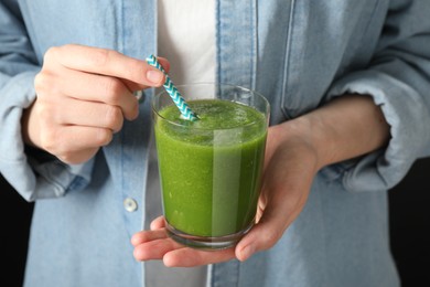Photo of Superfood. Woman with glass of tasty smoothie against black background, closeup