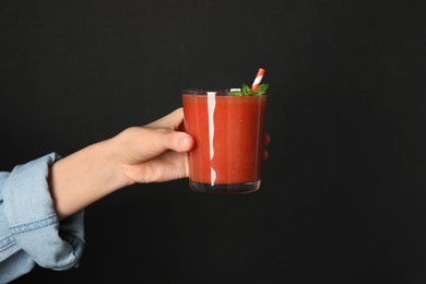 Photo of Superfood. Woman with glass of tasty smoothie against black background, closeup. Space for text