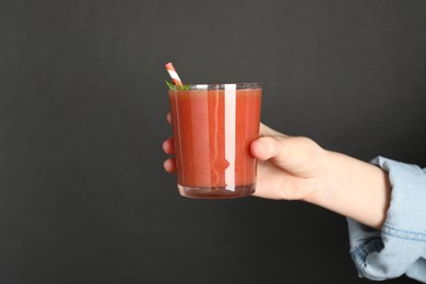 Photo of Superfood. Woman with glass of tasty smoothie against dark grey background, closeup. Space for text