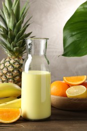 Photo of Superfood. Refreshing smoothie in bottle and ingredients on wooden table against grey background, closeup