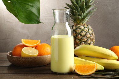 Photo of Superfood. Refreshing smoothie in bottle and ingredients on wooden table against grey background, closeup