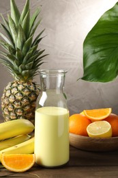 Photo of Superfood. Refreshing smoothie in bottle and ingredients on wooden table against grey background