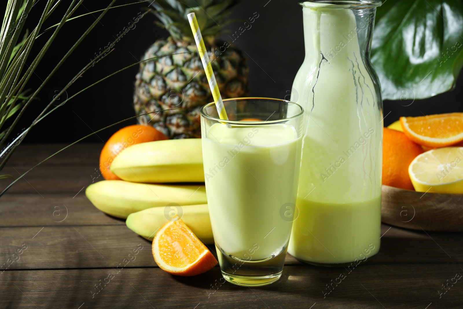 Superfood. Refreshing smoothie in bottle, glass and ingredients on wooden table against black background, closeup Photo of Superfood. Refreshing smoothie in bottle, glass and ingredients on wooden table against black background, closeup