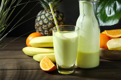 Photo of Superfood. Refreshing smoothie in bottle, glass and ingredients on wooden table against black background, closeup