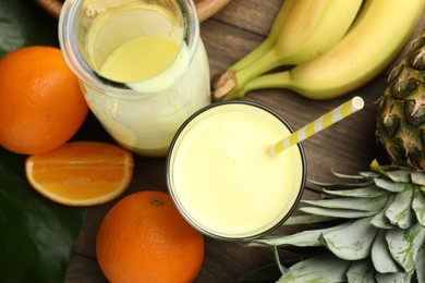 Photo of Superfood. Refreshing smoothie in bottle, glass and ingredients on wooden table, flat lay