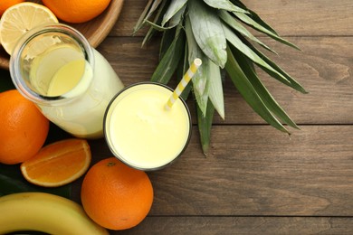 Photo of Superfood. Refreshing smoothie in bottle, glass and ingredients on wooden table, flat lay. Space for text