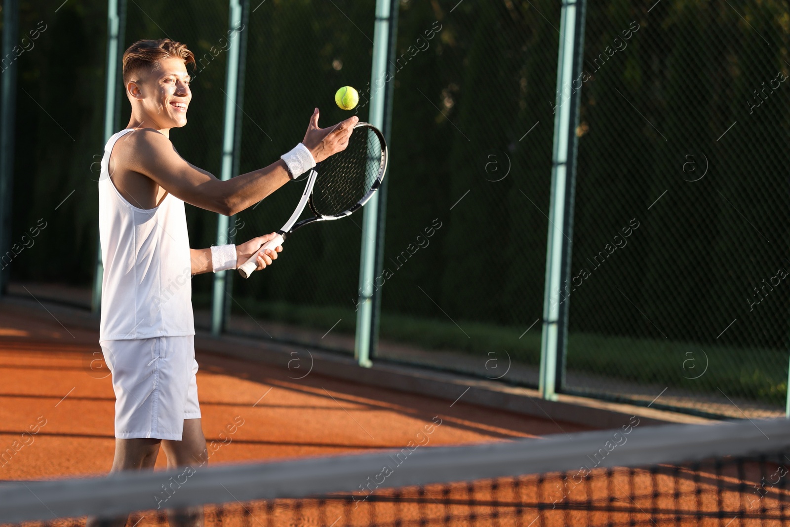 Young man playing tennis at court on sunny day. Space for text Photo of Young man playing tennis at court on sunny day. Space for text