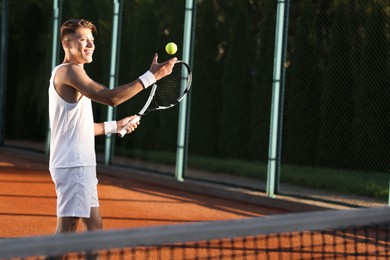 Photo of Young man playing tennis at court on sunny day. Space for text