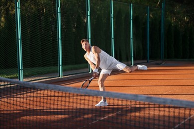Photo of Young man playing tennis at court on sunny day