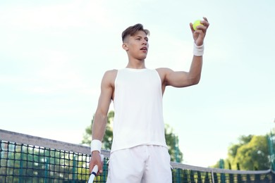 Photo of Young man playing tennis at court on sunny day, low angle view