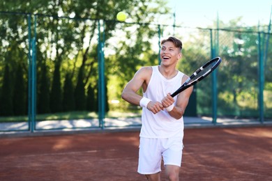 Photo of Young man playing tennis at court on sunny day. Space for text