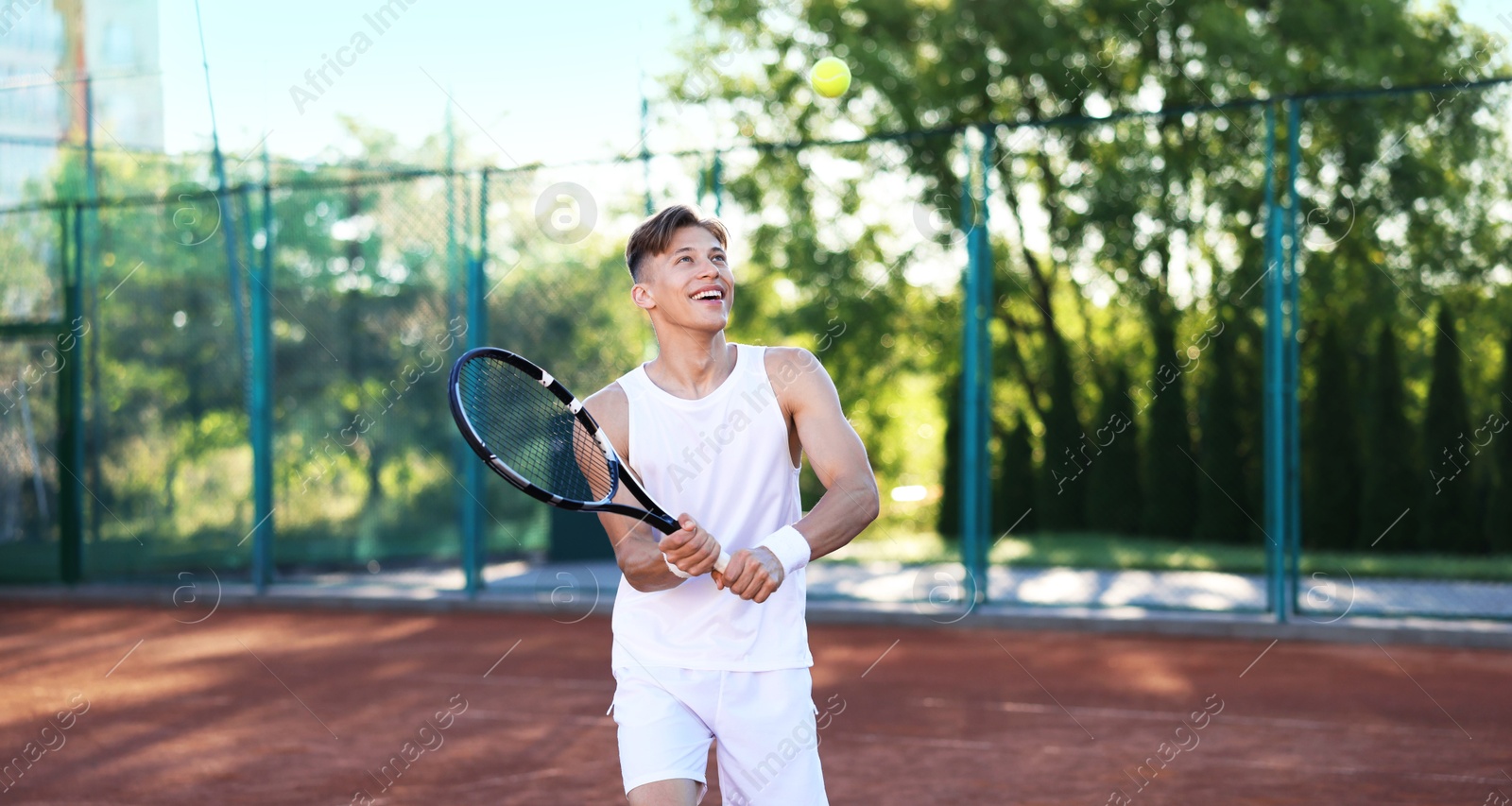 Young man playing tennis at court on sunny day Photo of Young man playing tennis at court on sunny day