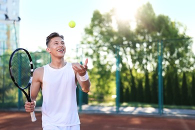 Photo of Young man playing tennis at court on sunny day. Space for text