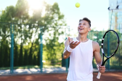 Photo of Young man playing tennis at court on sunny day. Space for text