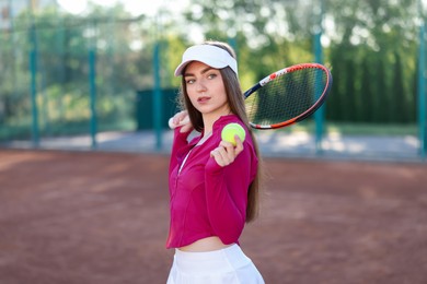 Photo of Beautiful woman with racket and ball at tennis court