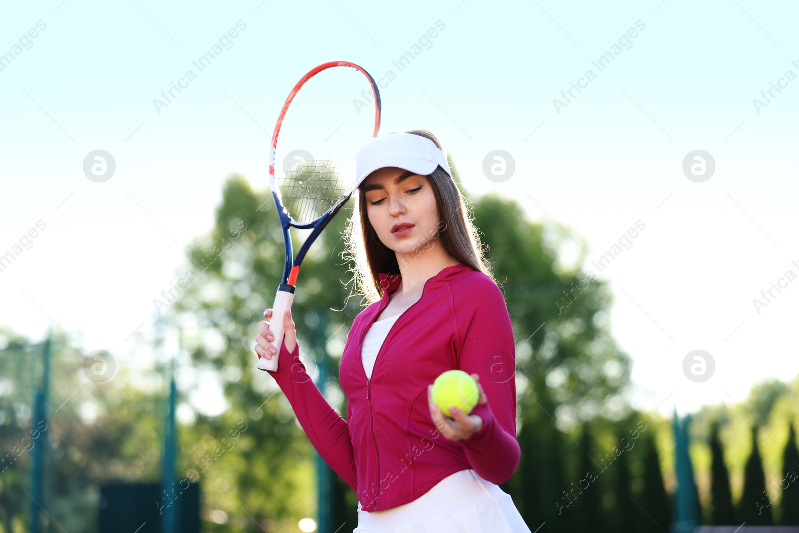 Beautiful woman with racket and ball at tennis court Photo of Beautiful woman with racket and ball at tennis court