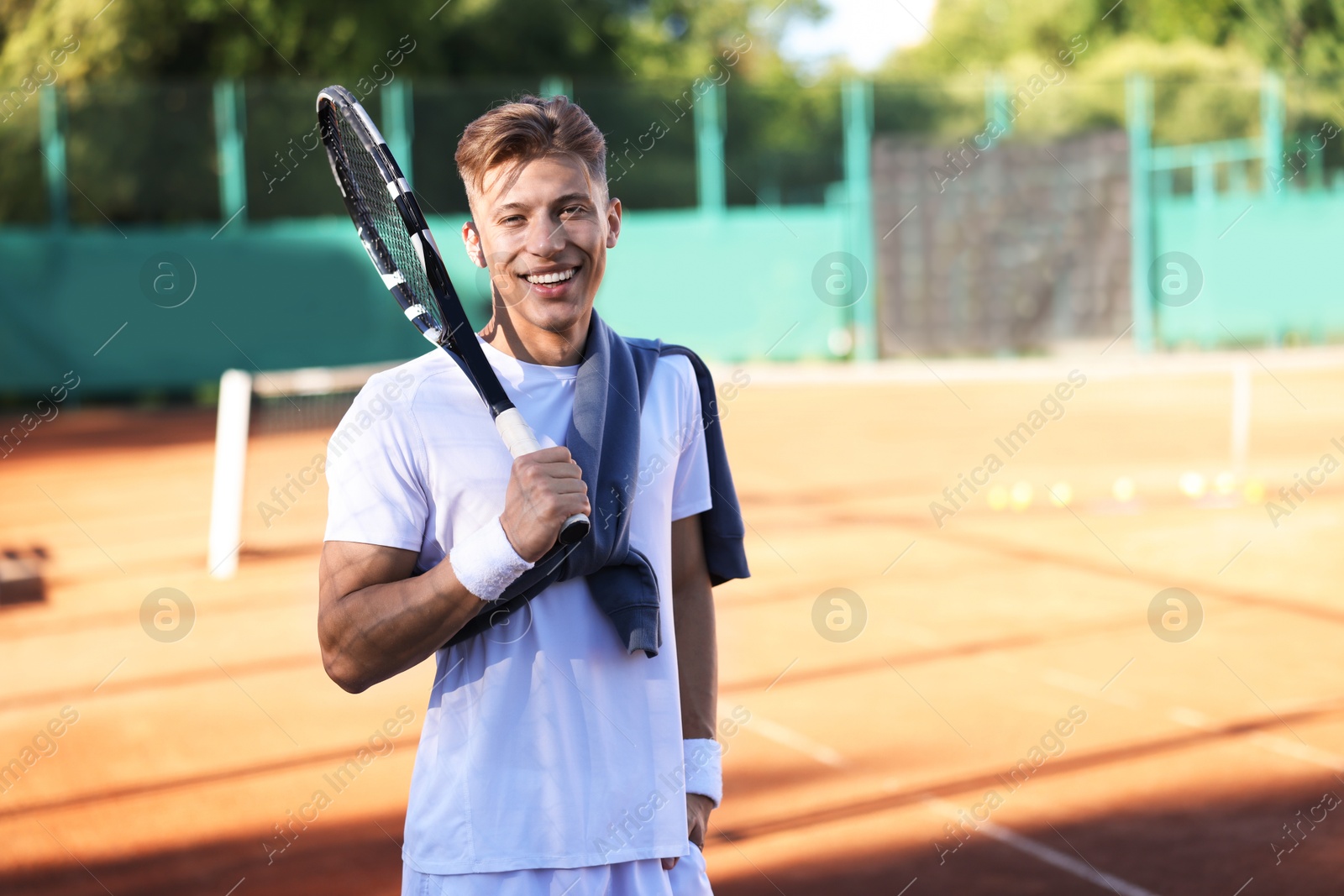 Young man with racket at tennis court. Space for text Photo of Young man with racket at tennis court. Space for text