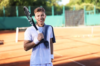 Photo of Young man with racket at tennis court. Space for text