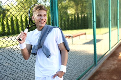 Photo of Young man with racket at tennis court. Space for text