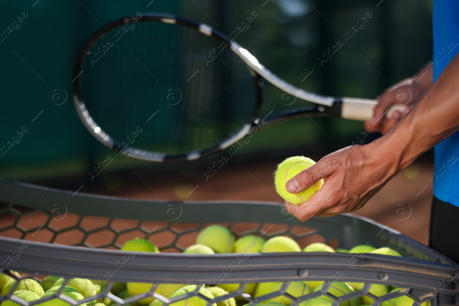 Man taking tennis ball out of cart at court, closeup Photo of Man taking tennis ball out of cart at court, closeup