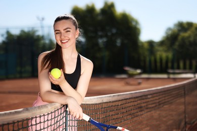 Photo of Happy woman with racket and ball at tennis court. Space for text