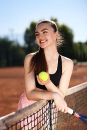 Photo of Happy woman with racket and ball at tennis court