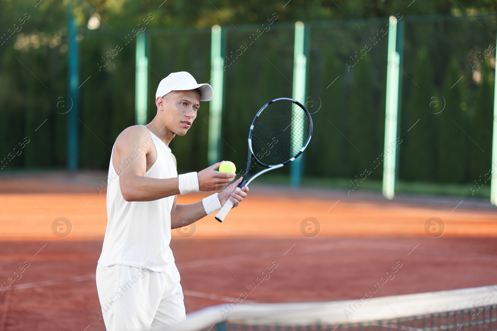 Young man playing tennis at court on sunny day Photo of Young man playing tennis at court on sunny day