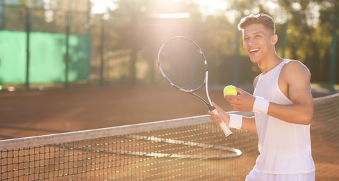 Photo of Young man playing tennis at court on sunny day. Space for text