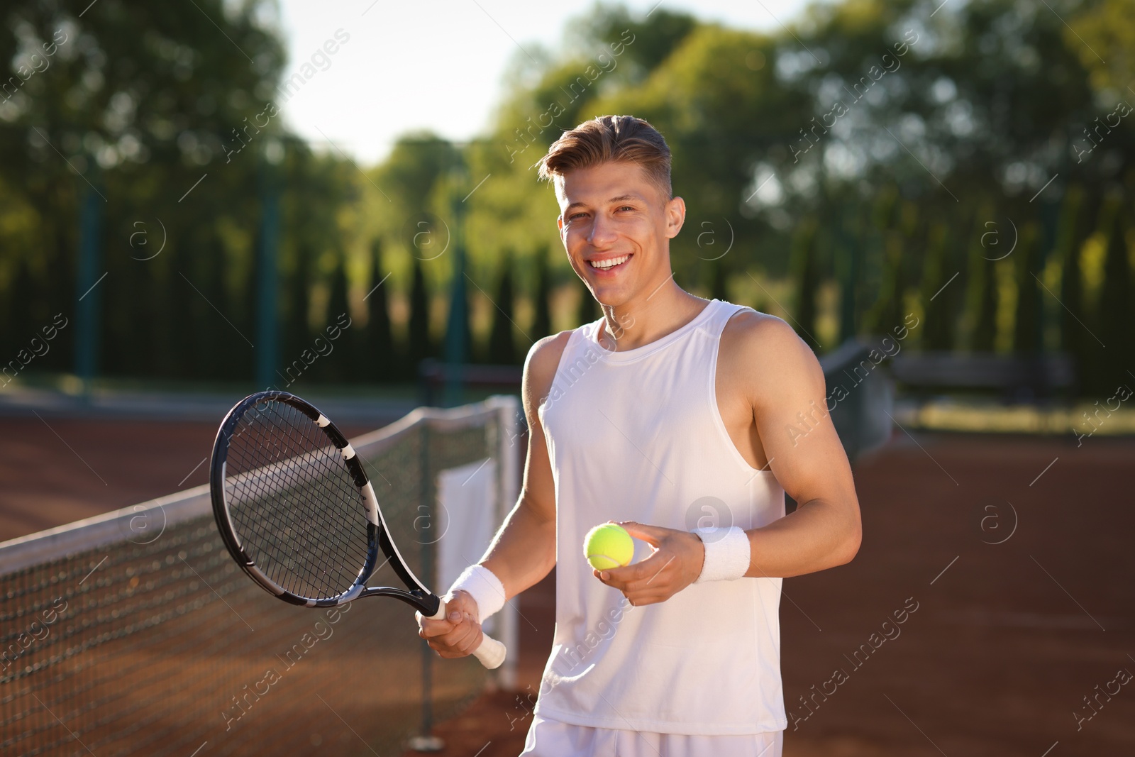 Happy man with tennis racket and ball at court Photo of Happy man with tennis racket and ball at court