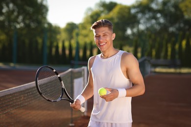 Photo of Happy man with tennis racket and ball at court
