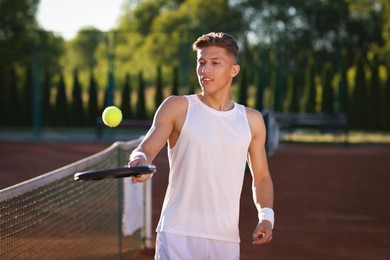 Photo of Young man playing tennis at court on sunny day