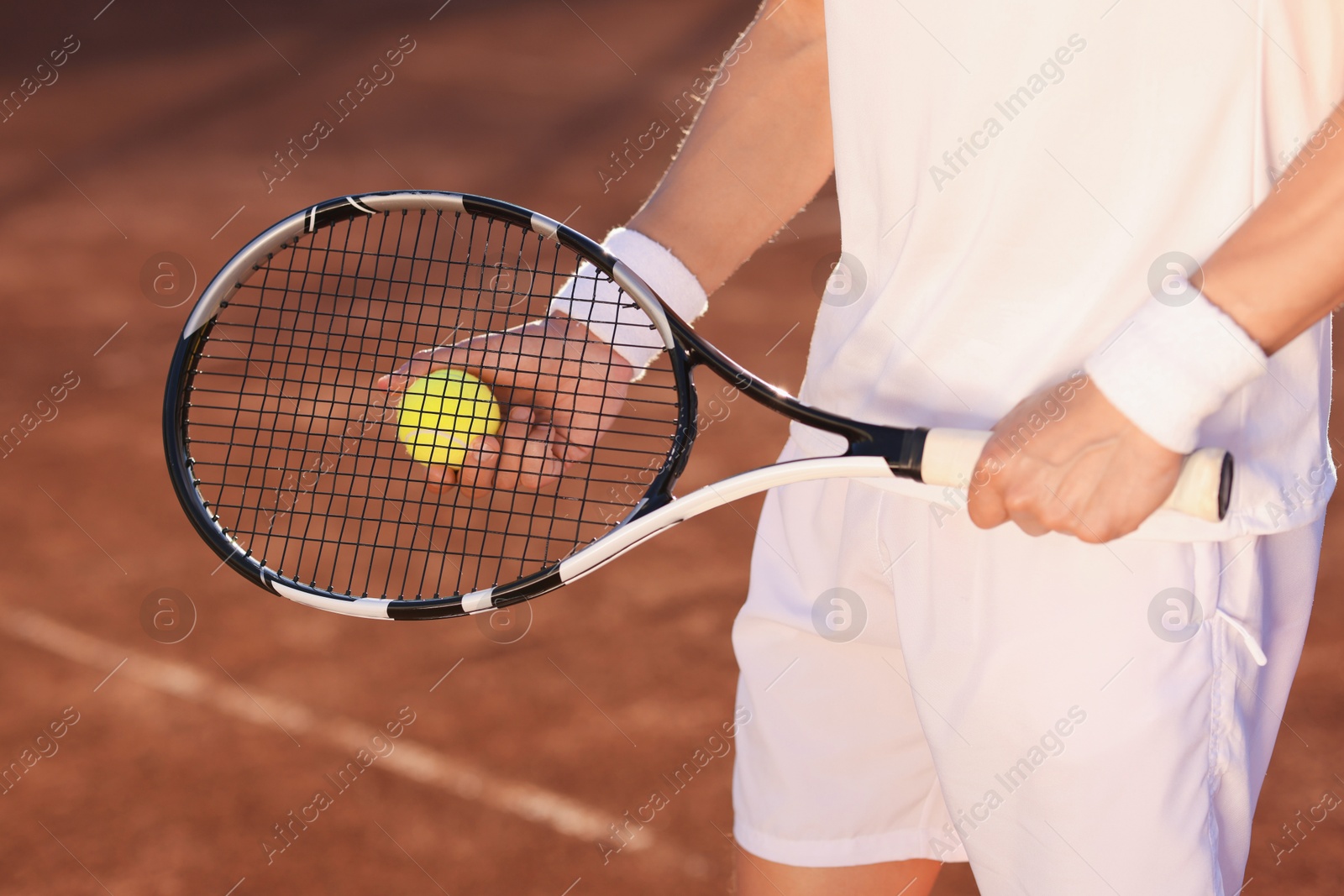 Man with tennis racket and ball at court, closeup Photo of Man with tennis racket and ball at court, closeup