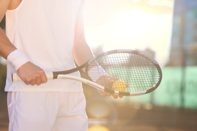 Photo of Man with tennis racket and ball at court on sunny day, closeup