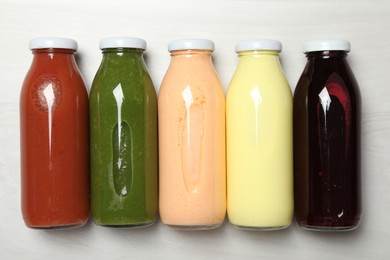 Photo of Superfood. Bottles with healthy drinks on light wooden table, flat lay