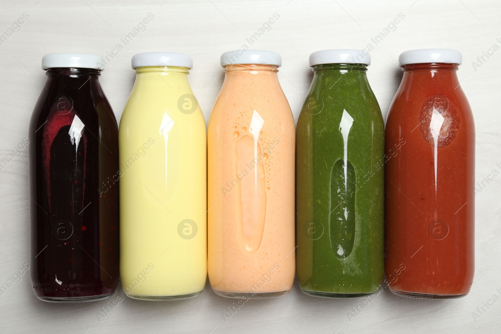 Superfood. Bottles with healthy drinks on light wooden table, flat lay Photo of Superfood. Bottles with healthy drinks on light wooden table, flat lay